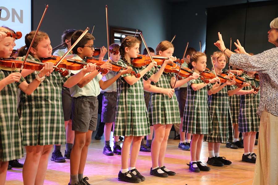 Music students performing a music piece on the violin, showcasing their musical talents and dedication